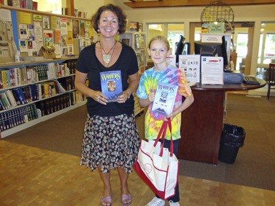 Librarian Karen Rogers awards Summer Reading Program participant Nora Zapalac with books.