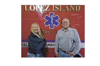 Rita and Chris Elliott stand in front of one of the EMS vehicles in the Lopez Island fire hall.