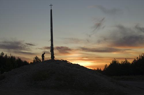 Pilgrim placing a stone at the Cruz de Ferro at sunrise. Pilgrims traditionally bring a stone or item from their home to place at this cross