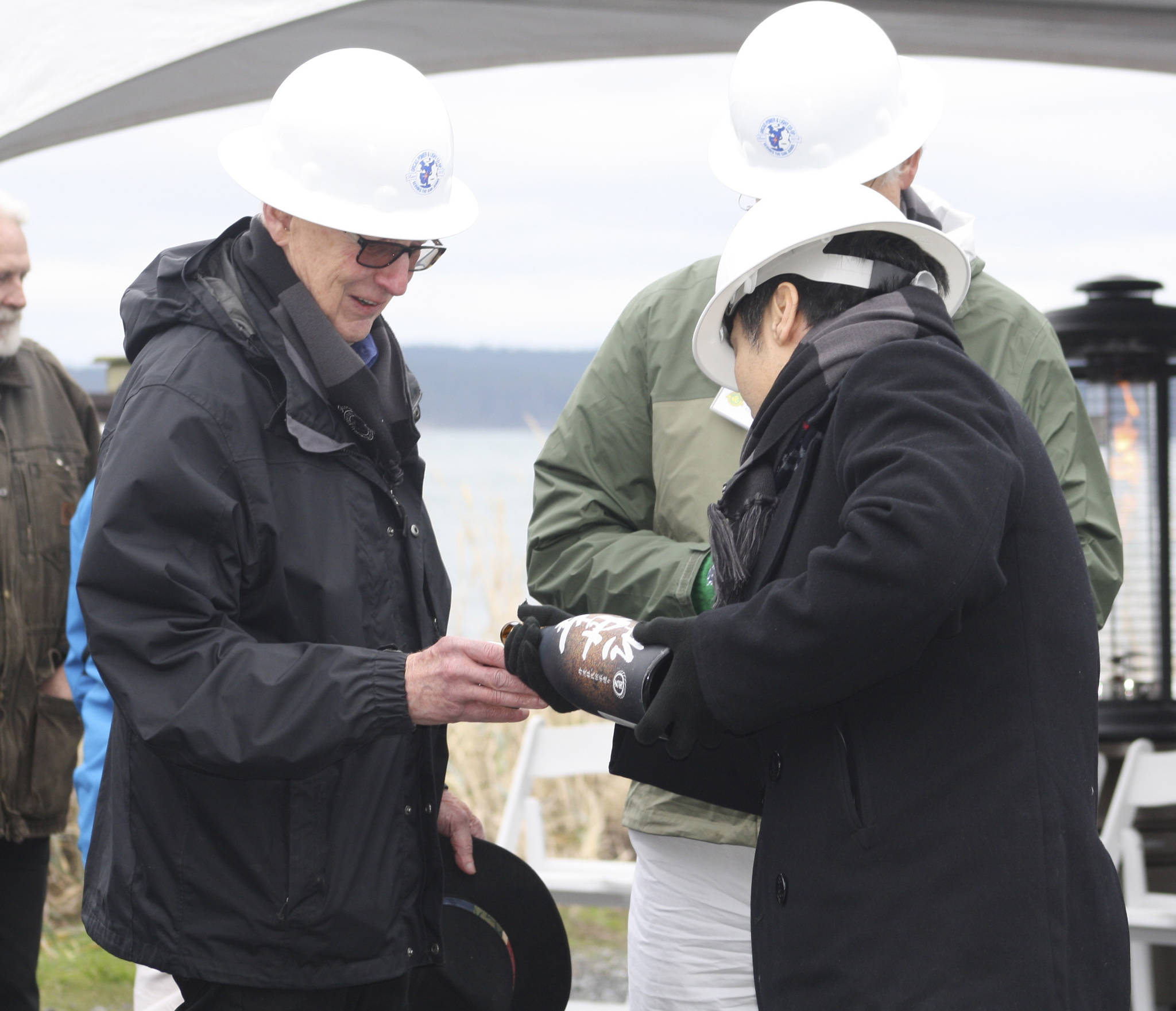 Staff photo/Hayley Day                                Keizo Takeo from the company that made the cable, Sumitomo Electric, pours sake for guests to celebrate the cable installation.