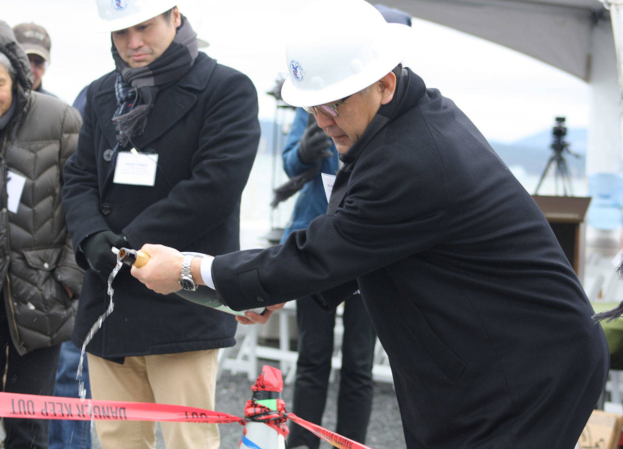 Staff photo/Hayley Day                                Kazuhira Harada from the company that made the cable, Sumitomo Electric, pours sake on the cable to celebrate its installation.