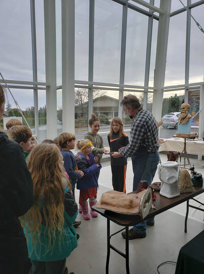 Contributed photo/SJIMA                                Above: Gareth Curtiss sculpts the face of the statue. Right: Gareth Curtiss shares work with onlookers at the museum.