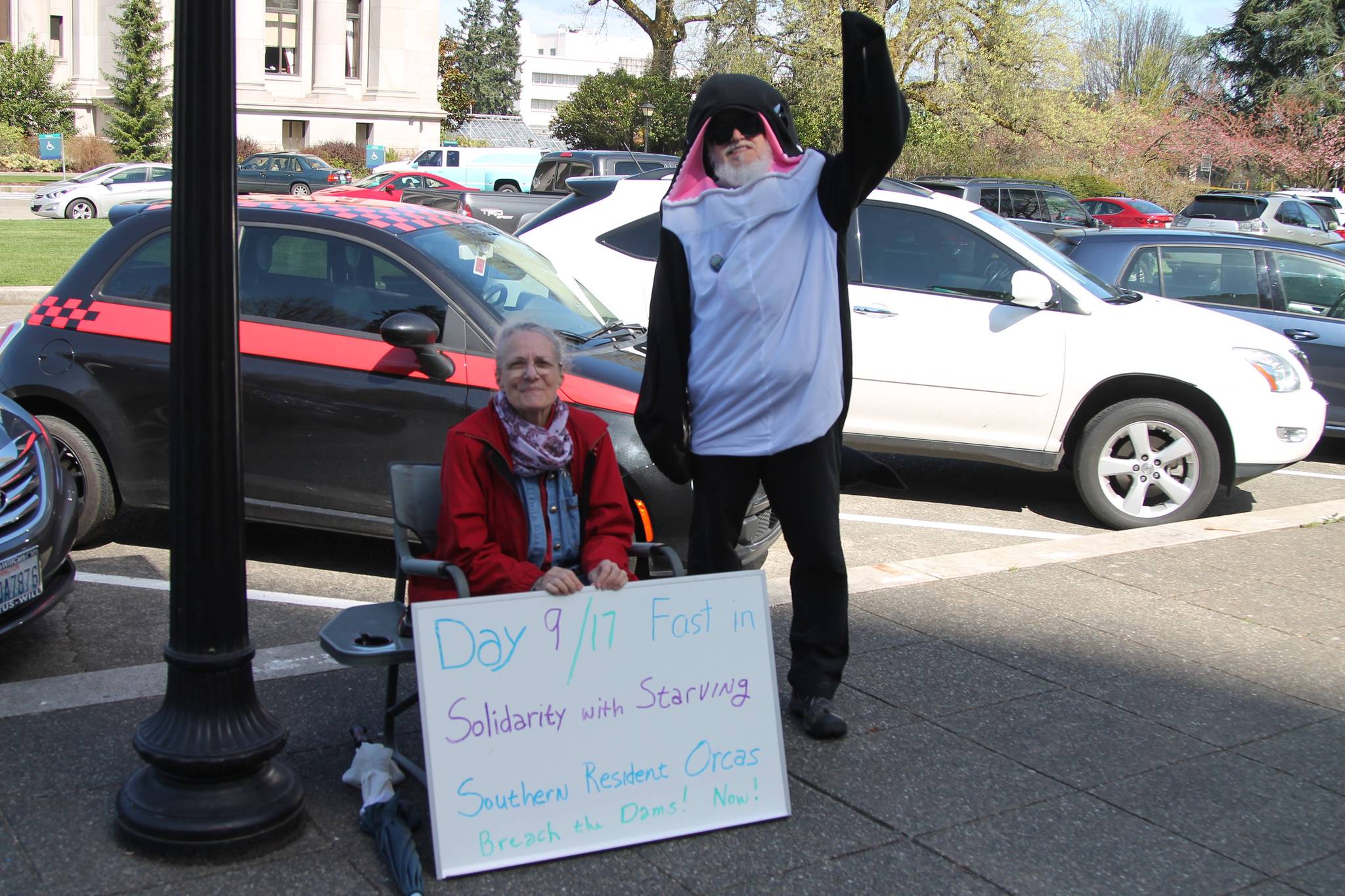 Contributed photo                                Lanni Johnson sitting in front of the capitol building steps where she has been on a hunger strike for the last 9 days to save the Southern Resident Orcas. Johnson is joined by supporter, Phil Myers, who can be seen in an orca onesie.