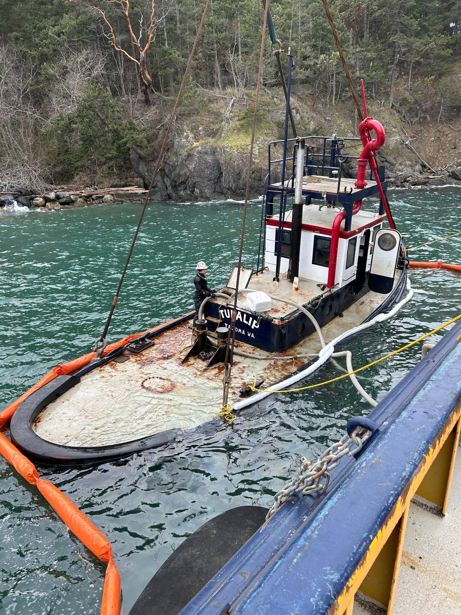Contributed photo.
The partially submerged Tugboat Tulalip suspended alongside a response vessel near the ferry terminal in preparation for removal.