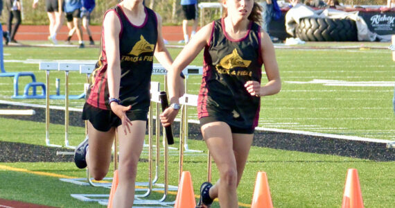 Contributed photo.
Anna Fuller takes the baton from Maya Briggs to anchor the 4 x 400 m relay. The team of Fuller, Briggs, Ruby McClean, and Lily Nicholas earned a slot at the District Finals in Coupeville.