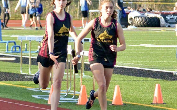Contributed photo.
Anna Fuller takes the baton from Maya Briggs to anchor the 4 x 400 m relay. The team of Fuller, Briggs, Ruby McClean, and Lily Nicholas earned a slot at the District Finals in Coupeville.