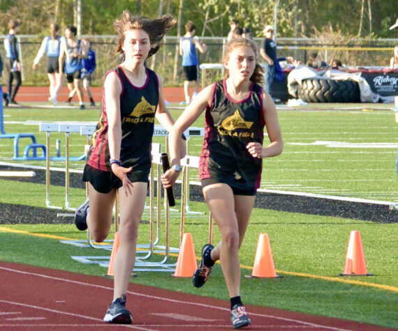 Contributed photo.
Anna Fuller takes the baton from Maya Briggs to anchor the 4 x 400 m relay. The team of Fuller, Briggs, Ruby McClean, and Lily Nicholas earned a slot at the District Finals in Coupeville.