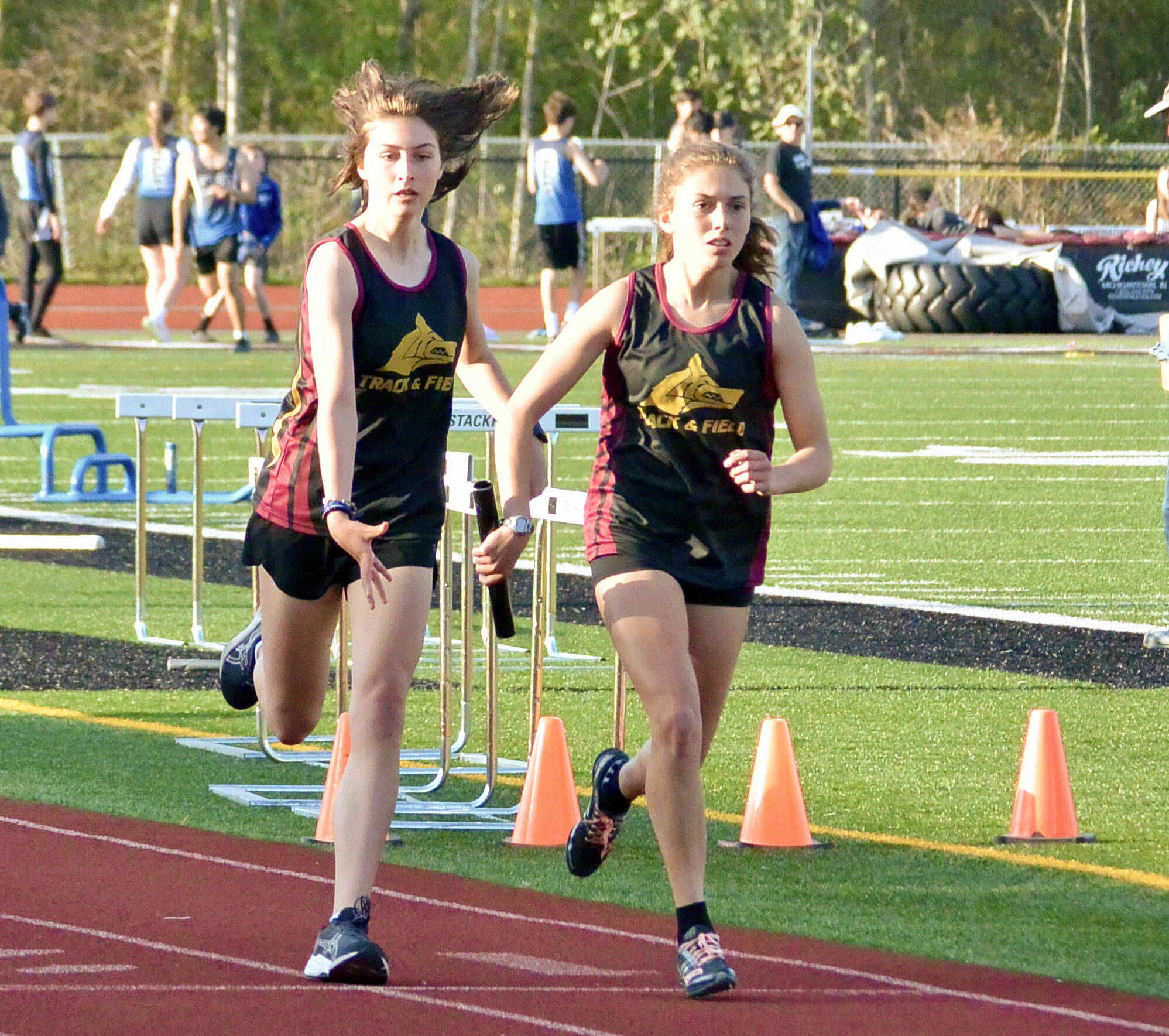 Contributed photo.
Anna Fuller takes the baton from Maya Briggs to anchor the 4 x 400 m relay. The team of Fuller, Briggs, Ruby McClean, and Lily Nicholas earned a slot at the District Finals in Coupeville.