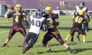 Rande Gruenwald (4) drops back to pass while Edwin Kramer (22) and Vinny Kramer (40) fend off Lummi rushers. The Blackhawks defeated the Lobos 66-28.
