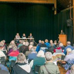 Photo Attribution: Robert S. Harrison                                Peggy Means, at the podium, Christa Campbell, Charlie Janeway and Dr. Bob Wilson addressed the clinic&rsquo;s partner search, proposed public hospital district and national issues affecting our clinic.