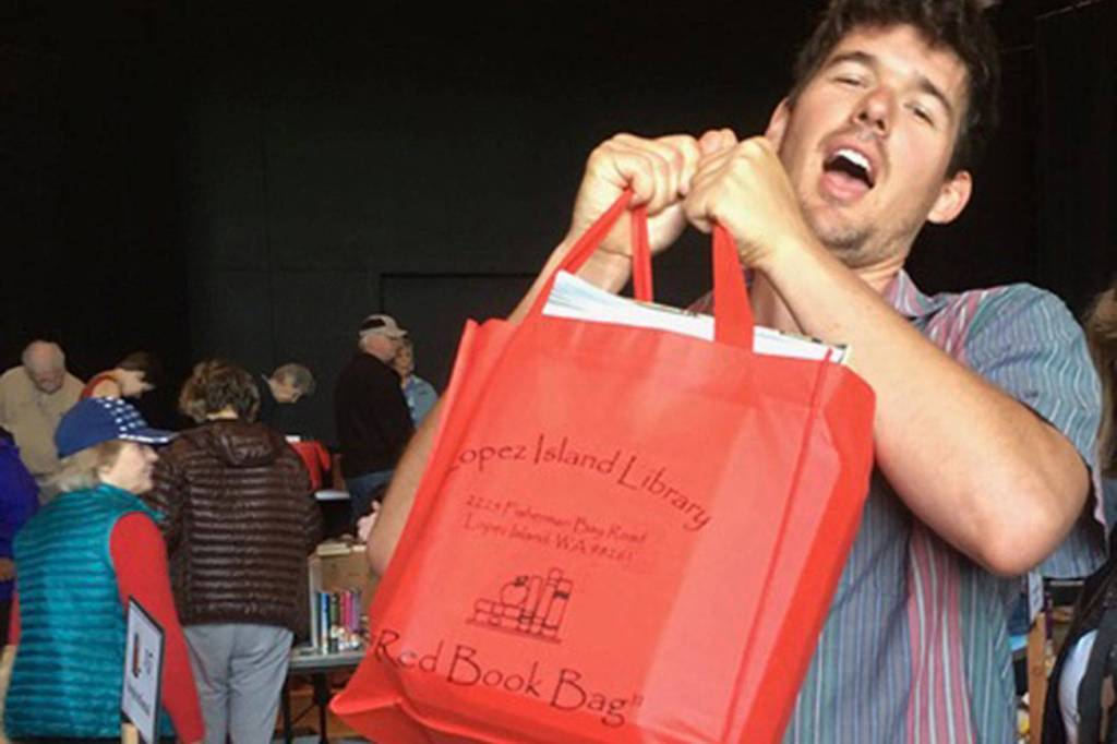 Contributed photo                                Charlie McGready hoists a full Red Bag in support of the Lopez Library Book Sale.